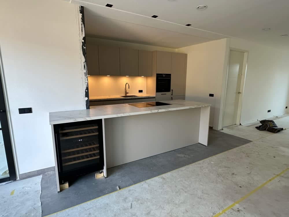 Witte keukenwand met wijnkoeler en hoge kasten